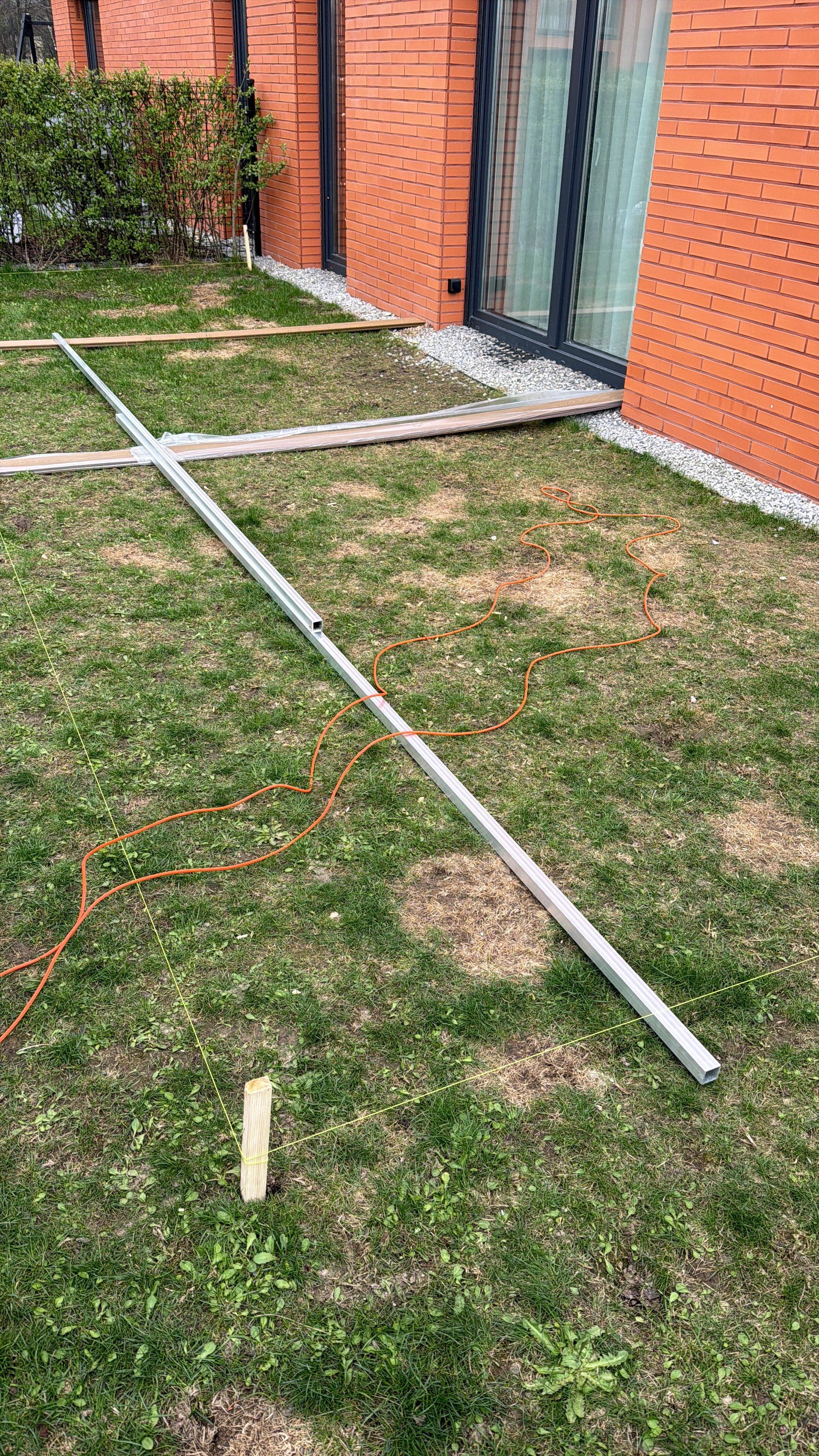 Aluminiowa poziomica i sznurki niwelacyjne na trawie — pomiar przed rozpoczęciem prac